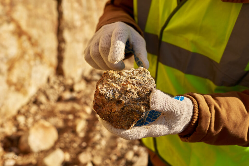 Miner wearing safety gear holding a large gold ore rock