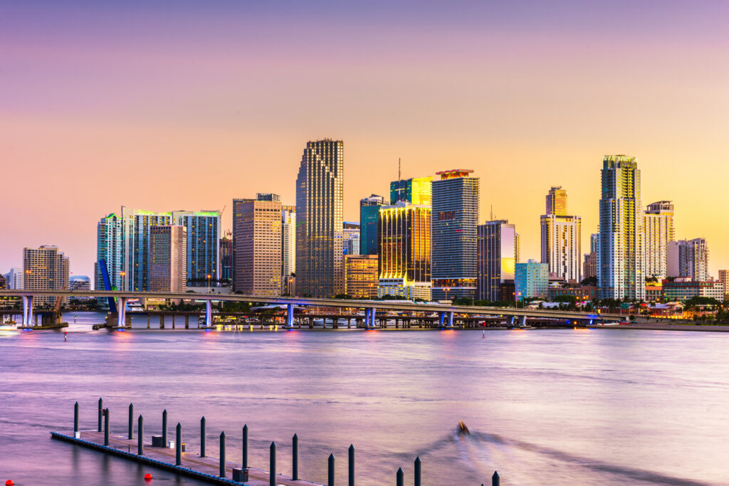 City skyline with tall buildings, a river below, and boats gently floating on the water
